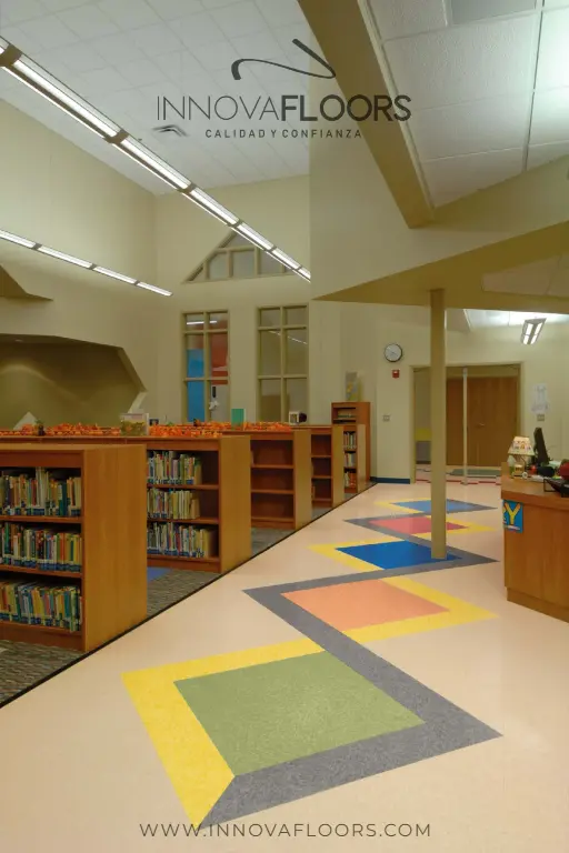 	Piso vinílico heterogéneo institucional con franjas gris, amarillo y rojo en ambiente de biblioteca