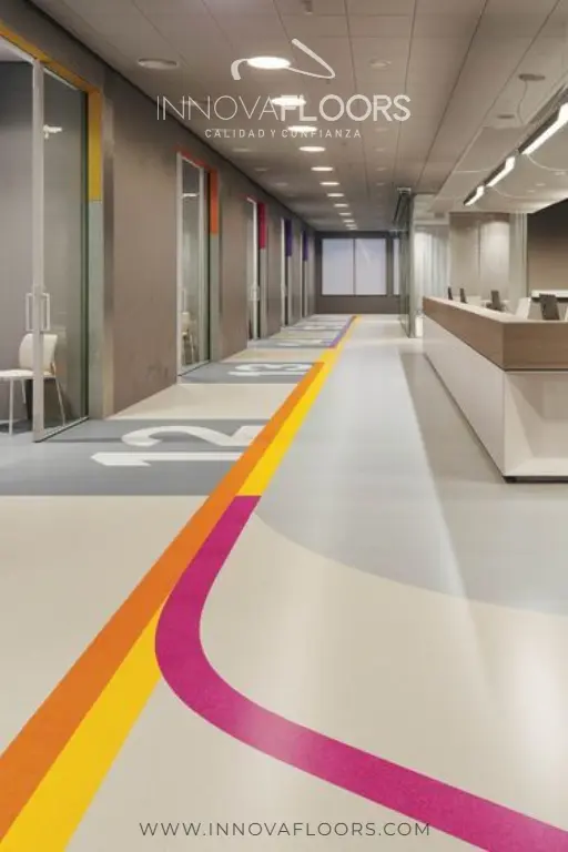 Piso vinílico homogéneo de uso institucional en pasillo, con franjas de color, ideal para hospitales, colegios, universidades, hoteles y gimnasios